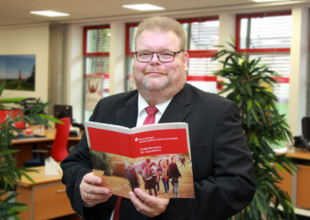 Christoph Weber von der Sparkasse am Niederrhein blättert im „Budgetkompass für Jugendliche“. Die 70-seitige Broschüre ist kostenfrei bestellbar – online oder telefonisch.