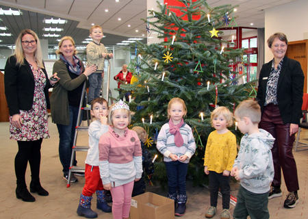 Sechs Kinder der evangelischen Kita schmückten den Tannenbaum in der Alpener Sparkasse. Kathrin Hüsch (v.l.n.r.), Myriam Pockrandt und Heike Letschert halfen mit.