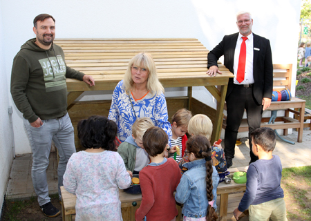 Moritz Launer vom Förderverein, die stellvertretende Kita-Leiterin Claudia Ukowski und Christian Jabs von der Sparkasse am Niederrhein inmitten einer Kinderschar, die sich über die neue Spielmöglichkeit auf dem Außengelände der Kita Kranichstraße freuen.