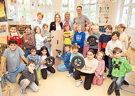 Im Seifenkisten-Rennstall der Klasse 4B an der Astrid-Lindgren-Schule packen alle mit an. Klassenlehrerin Svenja Bongardtz-Dittmer (ganz links) und Schulleiterin Manuela Gualano (2.v.r.) freuen sich über den Teamgeist. Isabell Winn von der Sparkasse (2.v.l.) durfte einen ersten Blick auf die Arbeiten unter der Leitung von Thomas Friebel werfen.